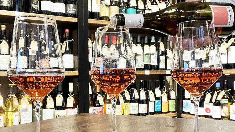 Calici di vino rosato naturale artigianale con sfondo di vigneti​